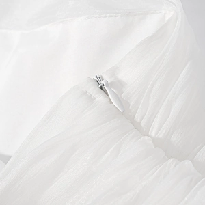 Close-up of invisible zipper detail on pleated white organza fabric for stylish skirt