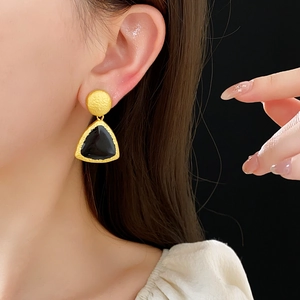 Detail of vintage geometric earrings with gold trim and black triangular pendants