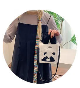 Detail of plush panda crossbody bag with panda face pattern and top handle worn by model