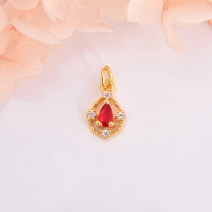 Macro shot of gold teardrop pendant with red pear-cut stone and tiny accent crystals