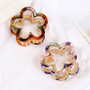 Detailed close-up of floral acetate hair claws in amber and purple marble textures