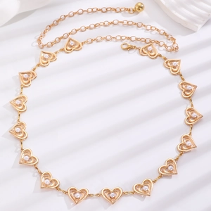 Detail of gold heart-shaped metal waist chain with white pearl inlays and lobster clasp