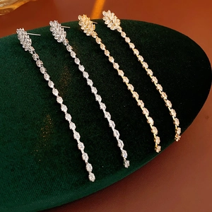 Detail of gold and silver leaf earrings with zirconia chain on green velvet
