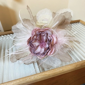 Macro detail of elegant lace flower hair claw with soft feathers and fabric petals
