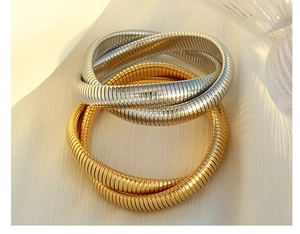 Detail of interlocking gold and silver snake bone bracelets with textured metal finish