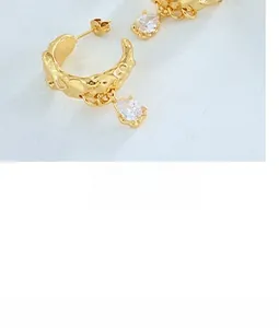 Close-up of gold textured hoop earrings with pear-cut zirconia stone pendants