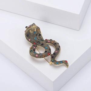 Detailed view of cobra brooch with multicolored rhinestones on a white geometric stand