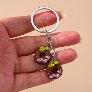 Close-up of a keychain featuring two chocolate donuts with yellow roses and pink vines