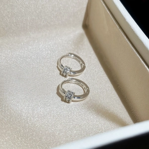 Macro shot of silver plated round hoop earrings with sparkling cubic zirconia on silk