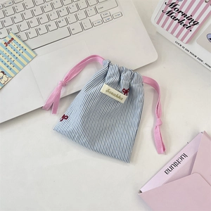 Détail du pochon en toile rayée bleue avec cordon rose et broderie nœud rouge
