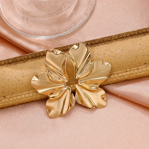 Macro shot of large golden matte flower earring with textured irregular metal petals