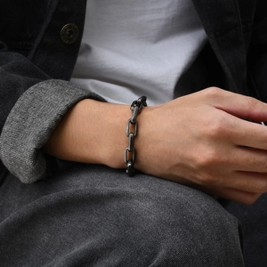 Close-up of a minimalist gunmetal grey stainless steel box chain bracelet on a wrist