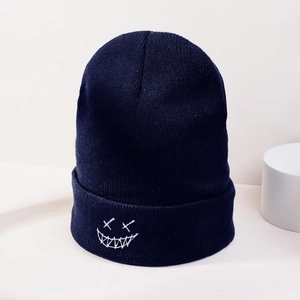 Detailed view of the white devil smile embroidery on a thick navy blue knitted beanie hat
