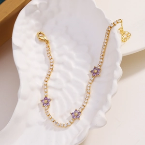 Macro detail of gold flower bracelet with pavé cubic zirconia and purple petals