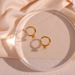 Detailed view of gold hoop earrings with clear cubic zirconia on champagne silk backdrop