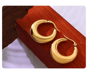 Primo piano di moderni orecchini a cerchio a U placcati in oro 18K con finitura lucida