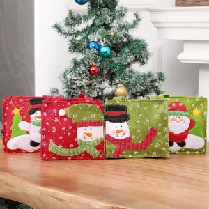 Set of four felt Christmas gift bags with snowman and Santa embroidery on wood table
