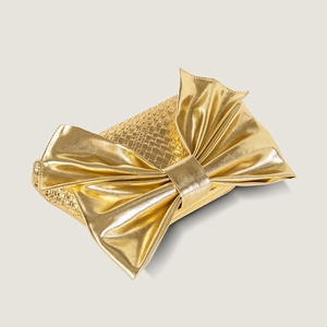 Detail of gold woven leather clutch bag with a large bow decoration for evening parties