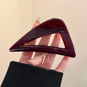 Large burgundy triangle hair claw clip in glossy acrylic shown being held for size