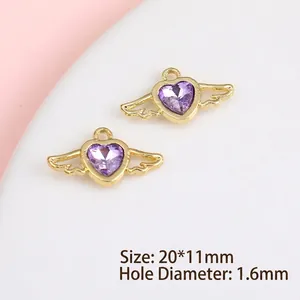 Macro view of gold-plated wing heart charms with purple faceted stones for DIY jewelry