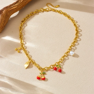 Golden fruit series necklace with cherry, pearl and leaf charms on textured background