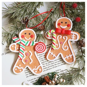 Macro detail of two gingerbread man resin ornaments on a vintage book with pine cones