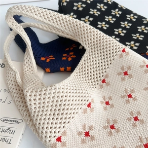 Dettaglio della borsa in maglia beige con design a rete traforata e motivi floreali rossi