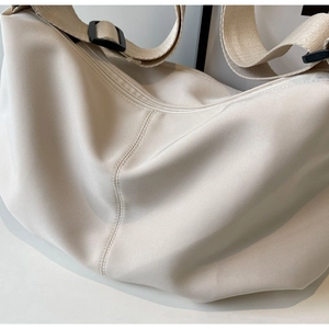 Detail of beige nylon tote showing fine texture, stitching, and adjustable black buckle
