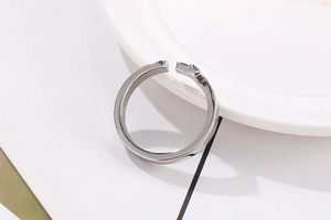 Macro shot of silver adjustable cross opening ring in polished stainless steel
