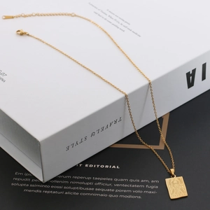 Close-up of golden Taurus zodiac rectangle pendant on a minimalist stainless steel chain
