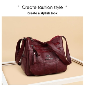 Detail view of wine red leather crossbody bag featuring textured finish and metal logo