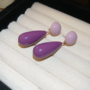 Detailed close-up of purple acrylic teardrop earrings on white jewelry gift box