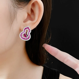 Close-up of a silver hollow gourd earring with pink and white cubic zirconia on a model