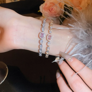 Detail view of gold and silver bracelets with pink oval gemstones and zircon accents