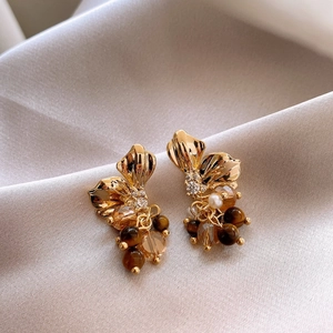 Macro detail of vintage gold earrings with tiger eye stone and crystal on silk fabric