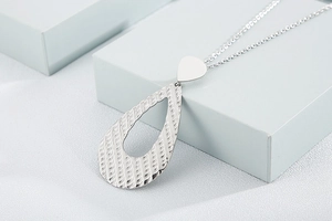 Macro detail of silver teardrop pendant with hollow structure and textured metal surface