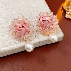 Detail of pink satin rose earrings with crystal beads and a white teardrop pearl