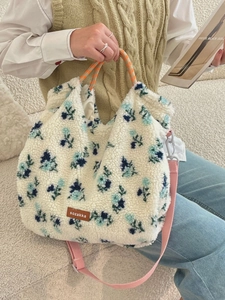 Fleece floral tote bag with orange checkered handles and pink strap shown on sofa