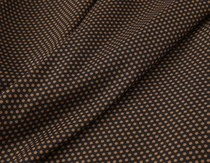 Détail d'un tissu fluide à pois marron sur fond noir avec un beau drapé