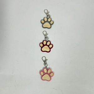 Detailed view of wooden paw print keychains in grey, red and pink with silver lobster clasps