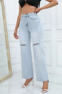 Detail shot of distressed light blue denim jeans with ripped knee and wide leg fit