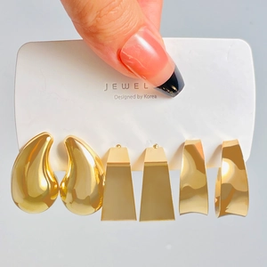 Close-up of three pairs of gold geometric earrings held on a branded display card