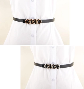 Detail of slim black leather belt featuring a stylish gold chain buckle on a white shirt