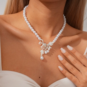 Elegant pearl necklace with diamond leaf and bow pendant worn on neck for a luxury style