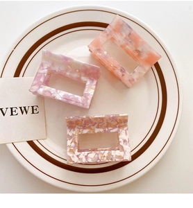 Close-up of three acetate hair claws with marble textures in a ceramic dish