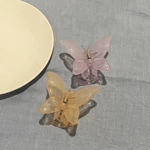 Close-up of translucent butterfly hair claws in amber and lavender resin with gold springs