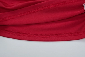 Vue macro détaillée du tissu tricoté rouge avec double couture sur l'ourlet de la robe