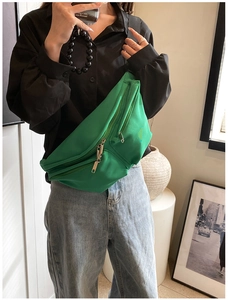Detail of green nylon crossbody bag with multiple zippers shown on a model