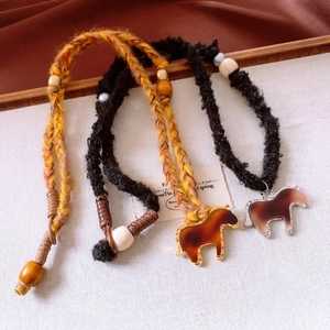 Close-up of woven horse pendants in yellow and black on a textured white background