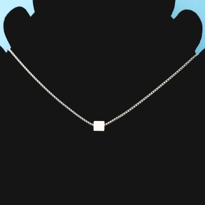 Detailed view of square pendant necklace on a jewelry display with a blue backdrop